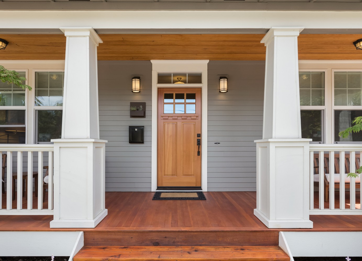 A front porch featuring white columns and a wooden door, creating a welcoming entrance to the home.