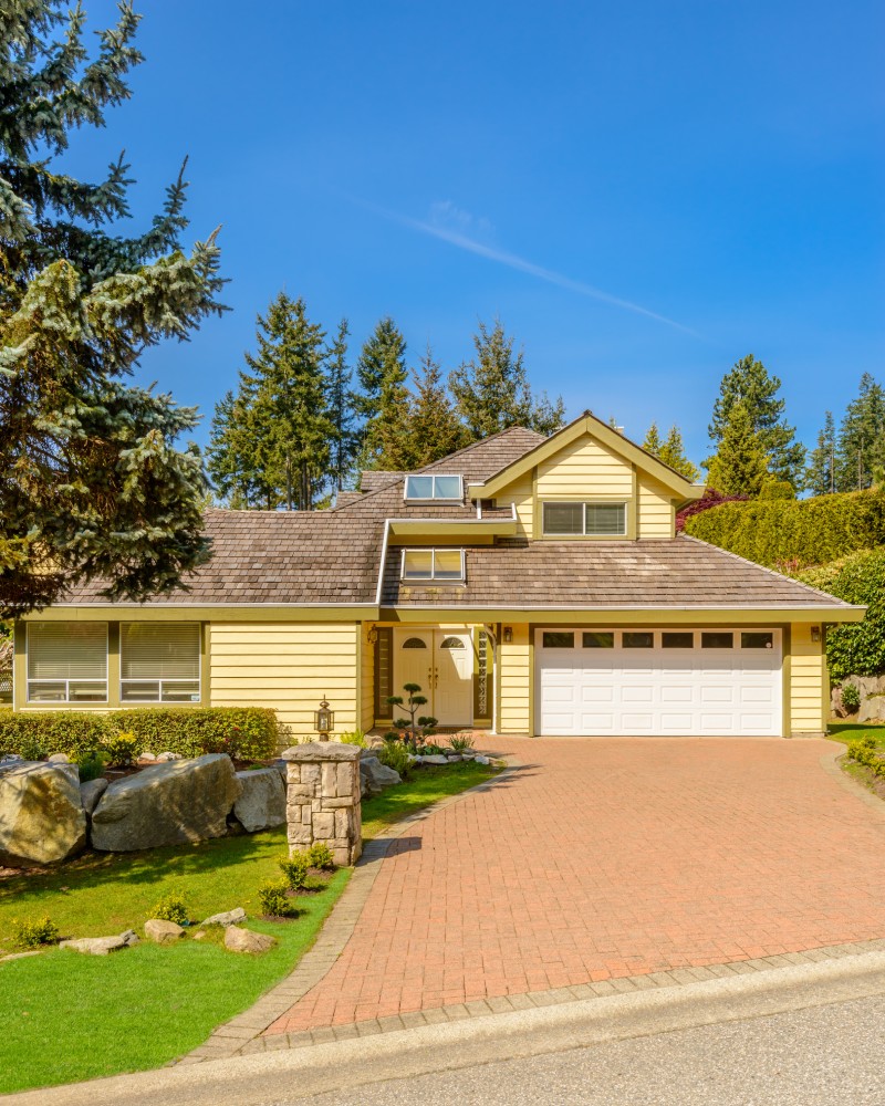A charming home featuring a driveway and a garage, surrounded by a well-maintained landscape.