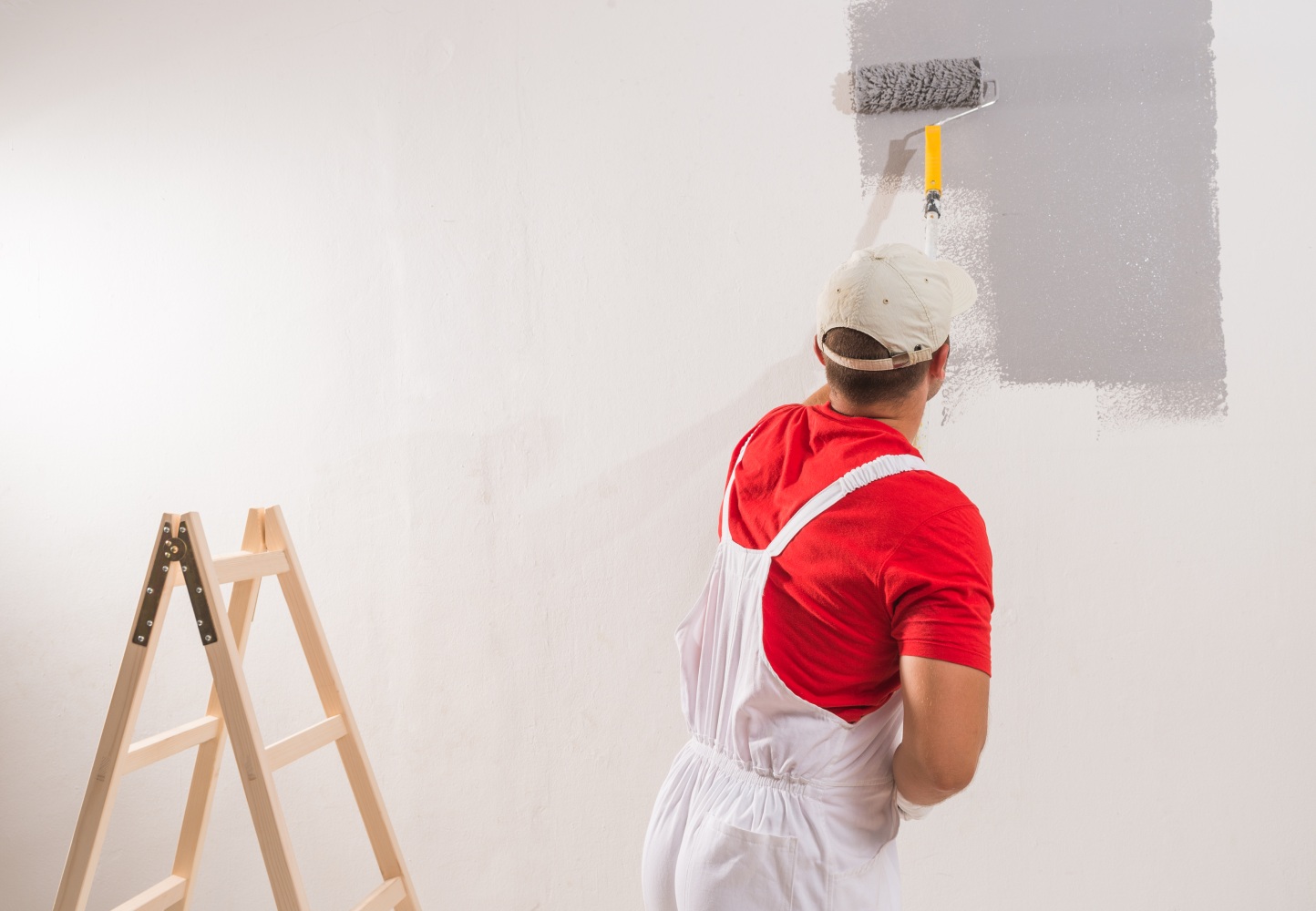 A man using a paint roller to apply paint to a wall in a home improvement setting.